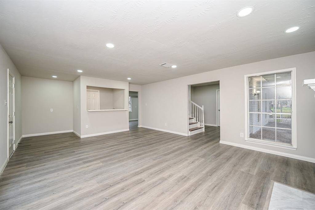 Just off your living space is the wet bar making entertaining a breeze!  View of living space, wet bar, stairs, large front door patio off the courtyard is your window view.