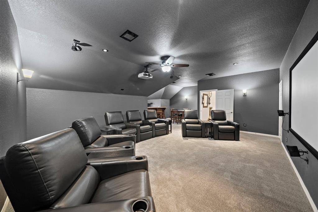 Cinematic experiences come to life in this sophisticated media room, where dark-toned walls and a thoughtfully designed layout enhance the theater-like ambiance. A built-in projector and screen set the stage for immersive entertainment, while recessed lighting and plush carpeting add to the cozy, high-end atmosphere. Perfect for movie nights, game days, or private screenings.