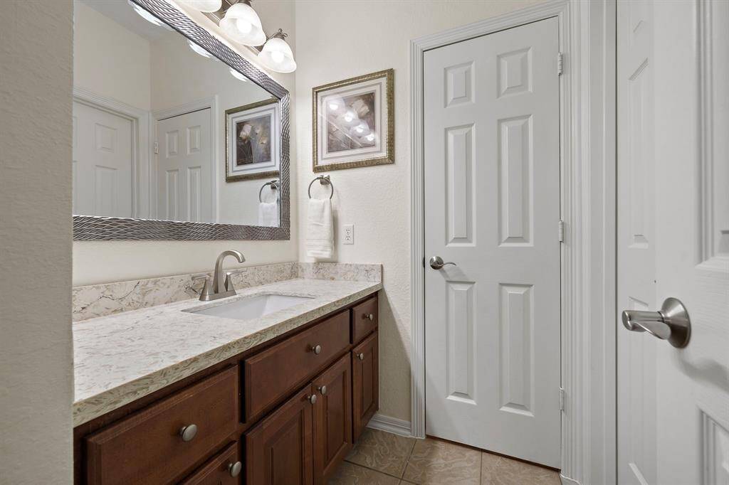 The secondary bath delivers neutral finishes and functionality with its updated vanity and light fixture. The updated quartz countertop and hardware pulls complement the wood cabinetry. Conveniently located near the game & media room.