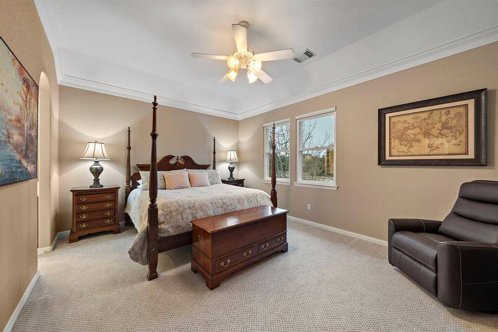 A serene retreat awaits in the spacious primary suite, where tray ceilings and large windows create an airy, light-filled ambiance. Plush carpeting adds warmth underfoot, while the well-appointed layout offers a peaceful escape with ample space for relaxation.