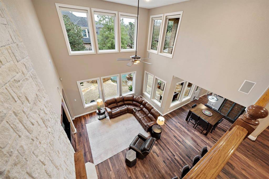 Expansive, open layout showcases the soaring ceilings and numerous windows offering views of the outdoor oasis. The elegant formal living area includes a fireplace, spacious seating, and beautiful hardwood floors.