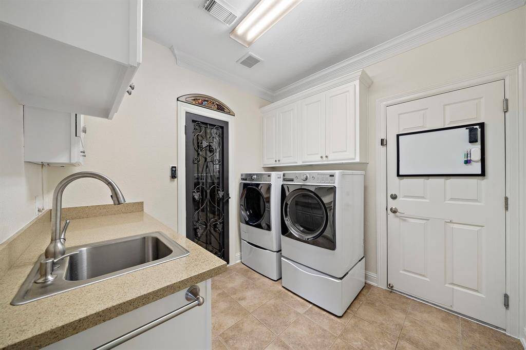 Dedicated utility room features a sink with ample counter space and upper cabinets for storage.