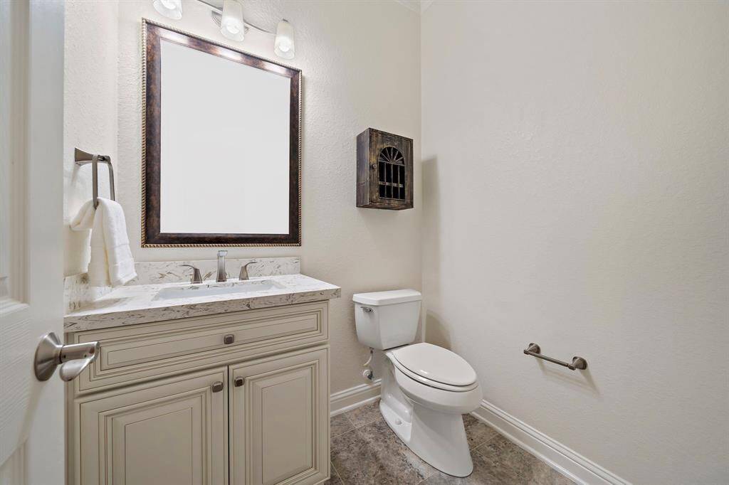 This half bath offers tile flooring, storage, and a framed vanity mirror.