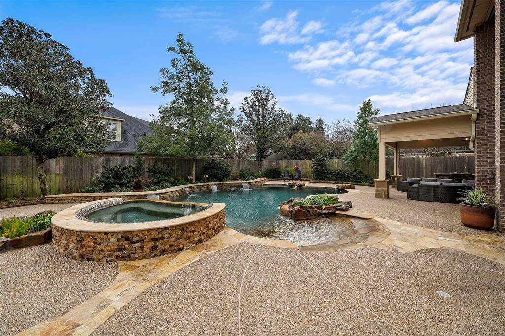 The heated pool and spa create a backyard oasis, and the covered patio features an outdoor kitchen. Stone paths lead to the seating areas, and the unique rock water feature adds to the entertainment value.