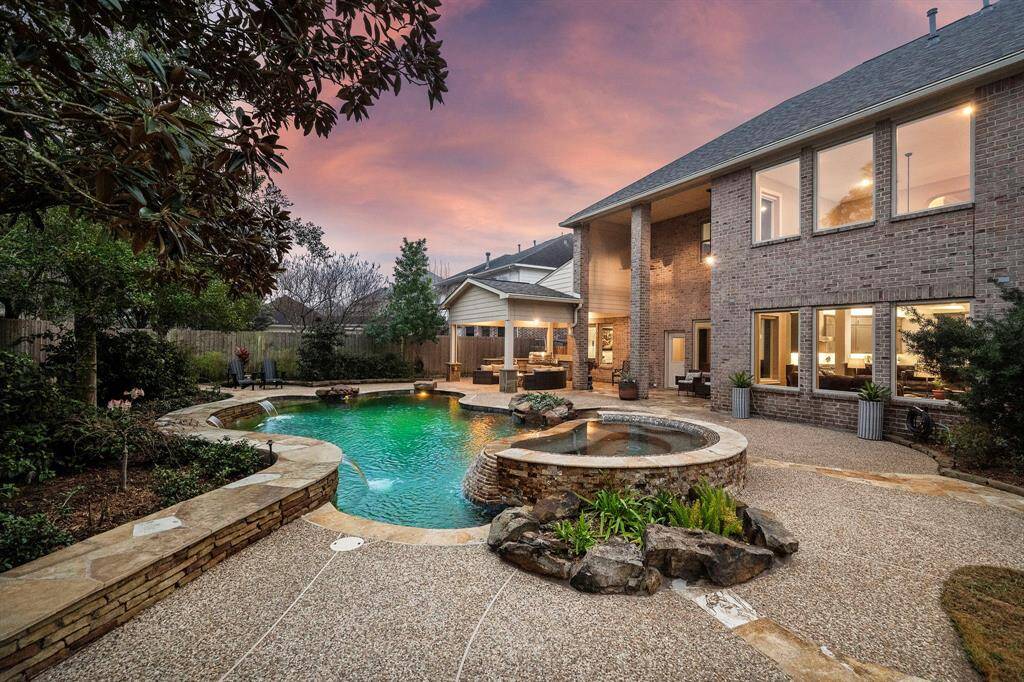 The backyard offers a heated pool plus a raised spa area with a rock waterfall feature. A covered outdoor kitchen and dining area provides distinct entertaining possibilities.
