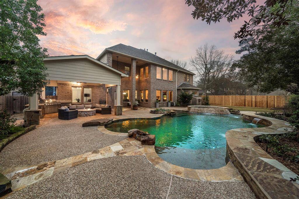 An expansive heated pool with stone-lined waterfalls defines this backyard oasis. The covered patio includes a fire pit and outdoor kitchen for entertainment. Step into luxury on this corner lot.