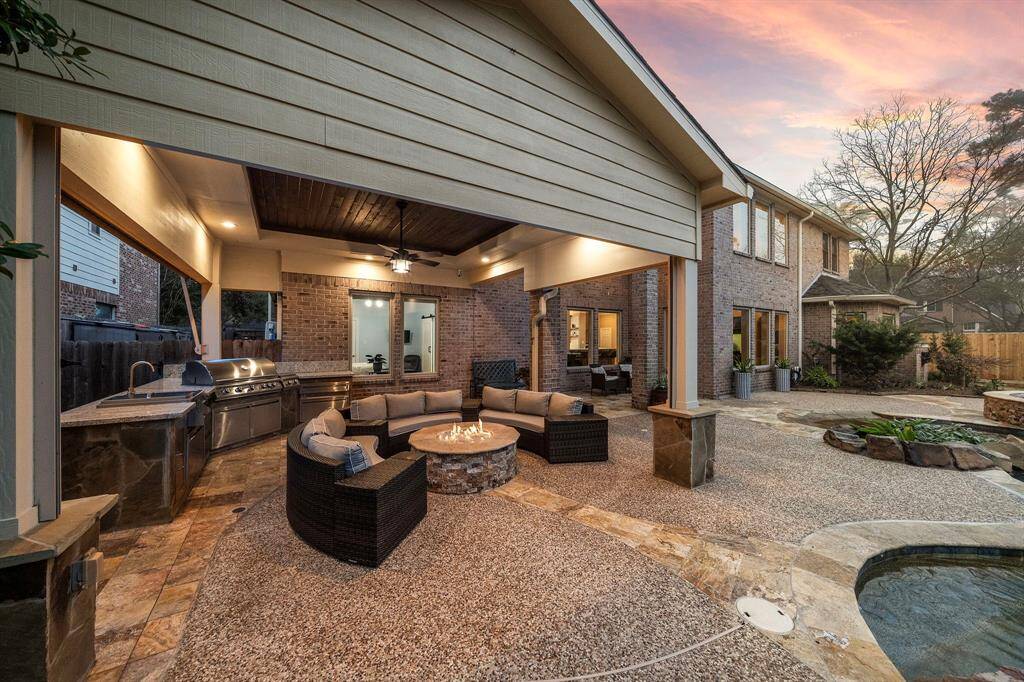 This spacious covered patio, with a stone fire pit is an entertainer's dream. The outdoor kitchen area includes professional-grade appliances, adding a gourmet touch to outdoor gatherings.