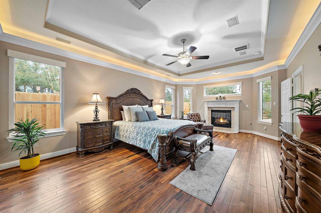 This primary suite is located on the first floor and includes a fireplace. Notice the elegant architectural details featuring wood floors with serene backyard views through large windows. The ensuite bath welcomes relaxation.