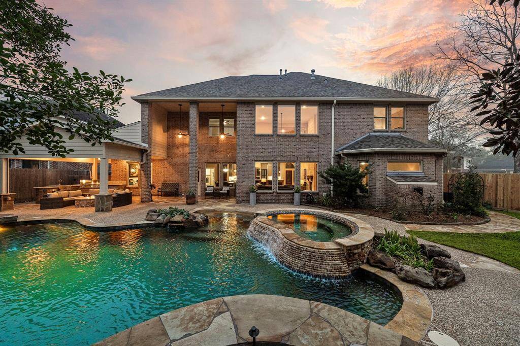 An outdoor living experience awaits with a heated pool, spa with cascading waterfall, and an expansive covered patio featuring a fire pit and summer kitchen. This backyard oasis offers beautifully landscaped touched generously gleaming with landscape lighting.