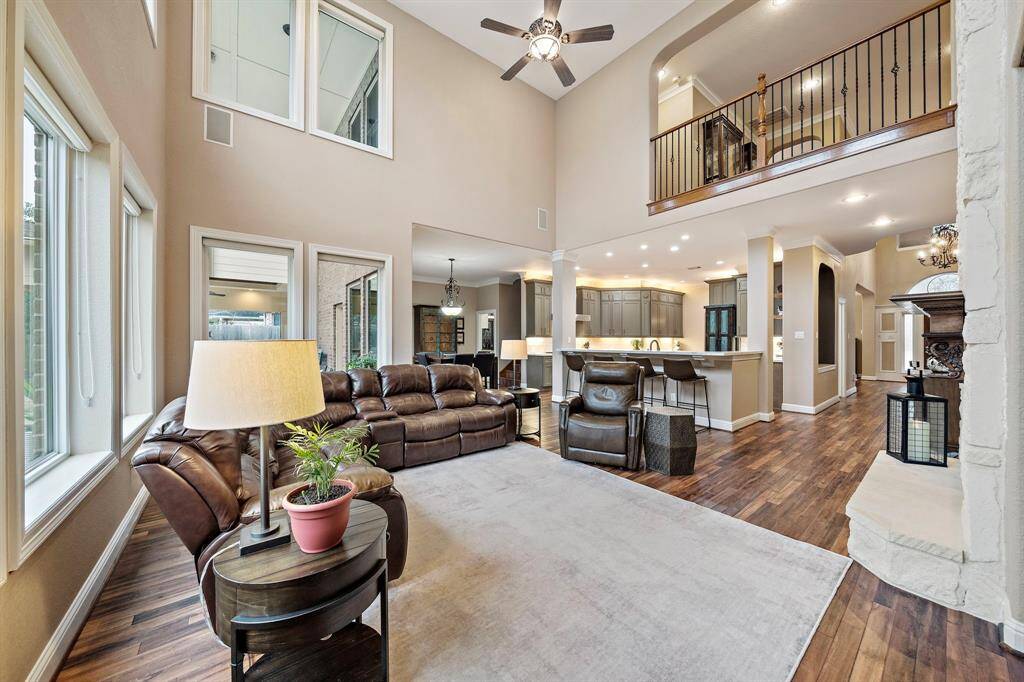 The spacious, first-floor living area features soaring ceilings and flows to entertainment areas. Notice the fireplace and elegant architectural details, including expansive windows revealing backyard views. The open layout provides abundant natural light.