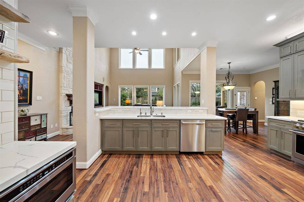 The kitchen, with a spacious dual sink and breakfast bar, seamlessly connects to the breakfast area and formal dining room. Updated flooring complements the open layout, while expansive cabinetry offers ample storage for kitchen essentials and the butler's pantry.