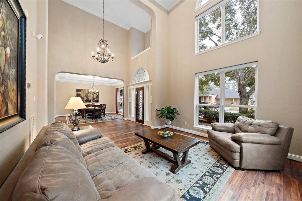 Dramatic two-story foyer featuring an elegant chandelier and front yard views through expansive windows. Flows to entertainment areas, the living area features dramatic ceilings w/ ample natural light and access to the formal dining space. Elegant architectural details provide a luxurious atmosphere.