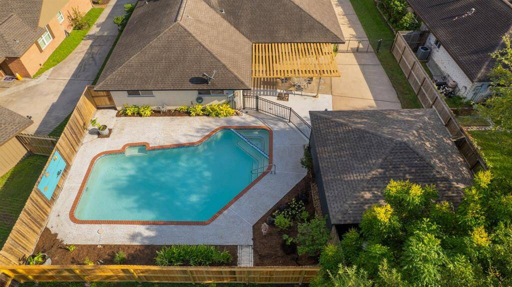 This aerial photo showcases a spacious backyard with an inviting pool and adjacent patio area, perfect for outdoor relaxation and entertainment.