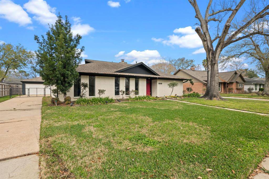 Large mature trees accent this well maintained home featuring a welcoming walkway and long drive.