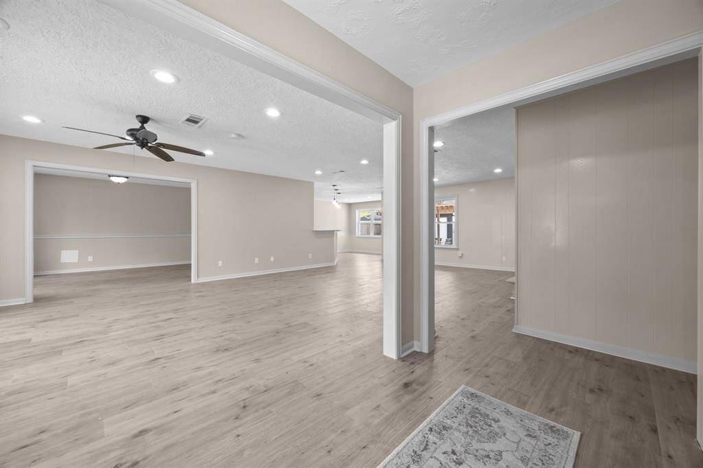View of large living space from the entry showcasing a spacious, open-concept interior with neutral colored walls and modern laminate flooring. The space is well-lit with a combination of recessed lighting and natural light.