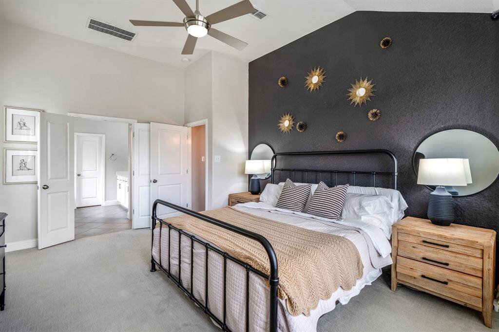 Relax and unwind in this stunning primary suite! The bold accent wall, bay window, and vaulted ceilings create the perfect retreat after a long day.
