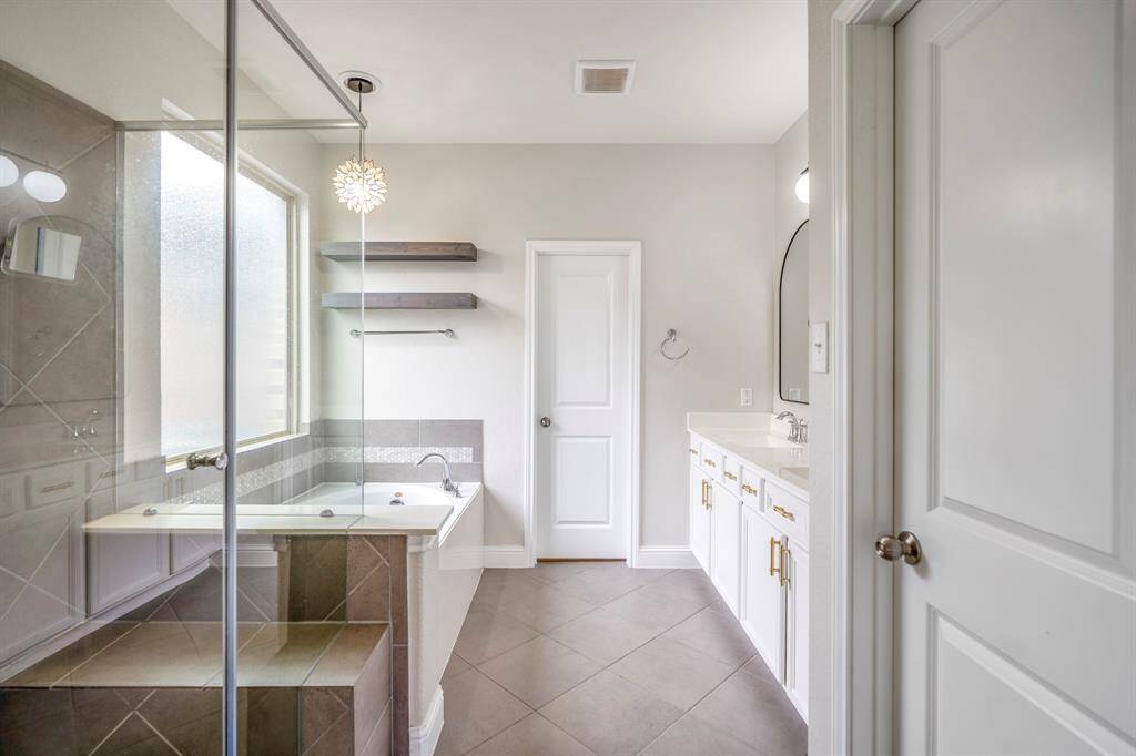 Step into comfort and style in this beautiful primary bathroom! Featuring a spacious walk-in shower with mud-set tile floors & glass surround, a serene garden tub, and floating wood shelves for a modern touch. Natural light completes the warm and inviting feel!