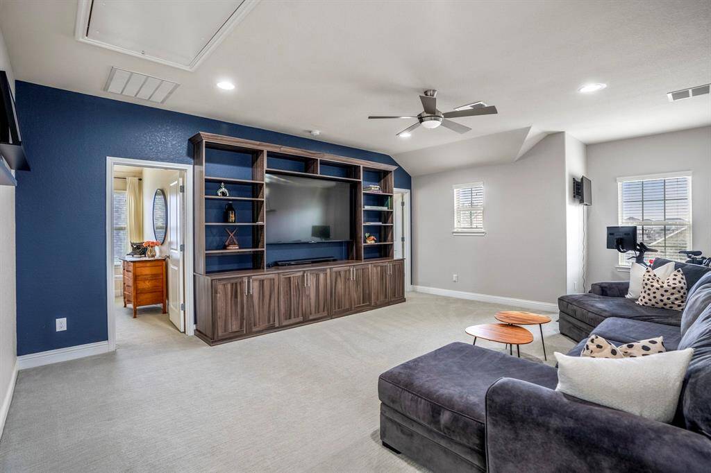 This spacious game room features plush carpet, recessed lighting, a ceiling fan, and a stylish accent wall—perfect for movie nights, game days, or just hanging out.