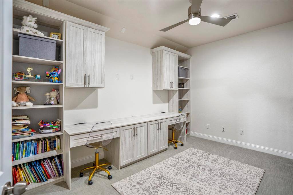 The media room, currently being used as a study, features recessed lights, plush carpet, and built-ins offering plenty of storage!
