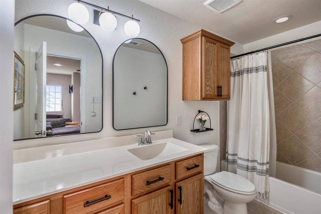 The full bathroom with wood cabinets, a spacious tub and shower, and large vanity, is located just off the secondary bedrooms, making it easy to share and the perfect place to unwind.