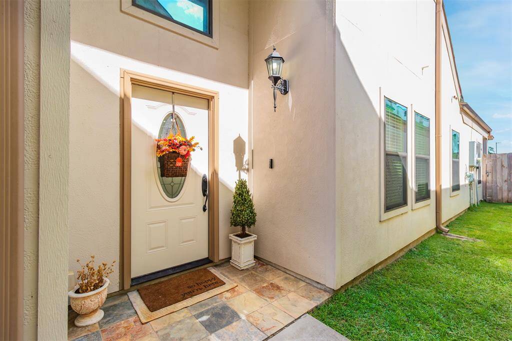 This photo showcases a welcoming front entrance with a decorative door and outdoor lighting. The entrance is flanked by windows providing natural light and a well-maintained lawn, creating an inviting atmosphere.