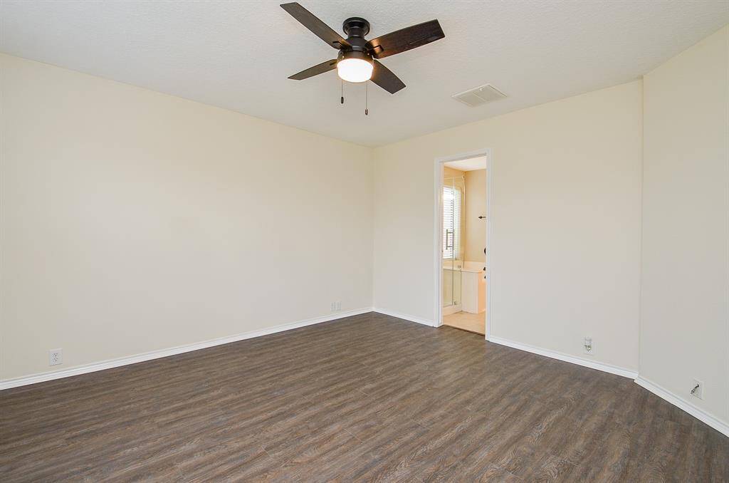 This room features freshly painted walls, wood flooring, and a modern ceiling fan. It has an attached bathroom, adding convenience and functionality.