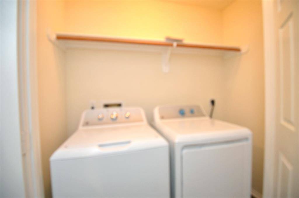This image shows a compact laundry area with a washing machine and dryer side by side. There's a shelf above for additional storage.
