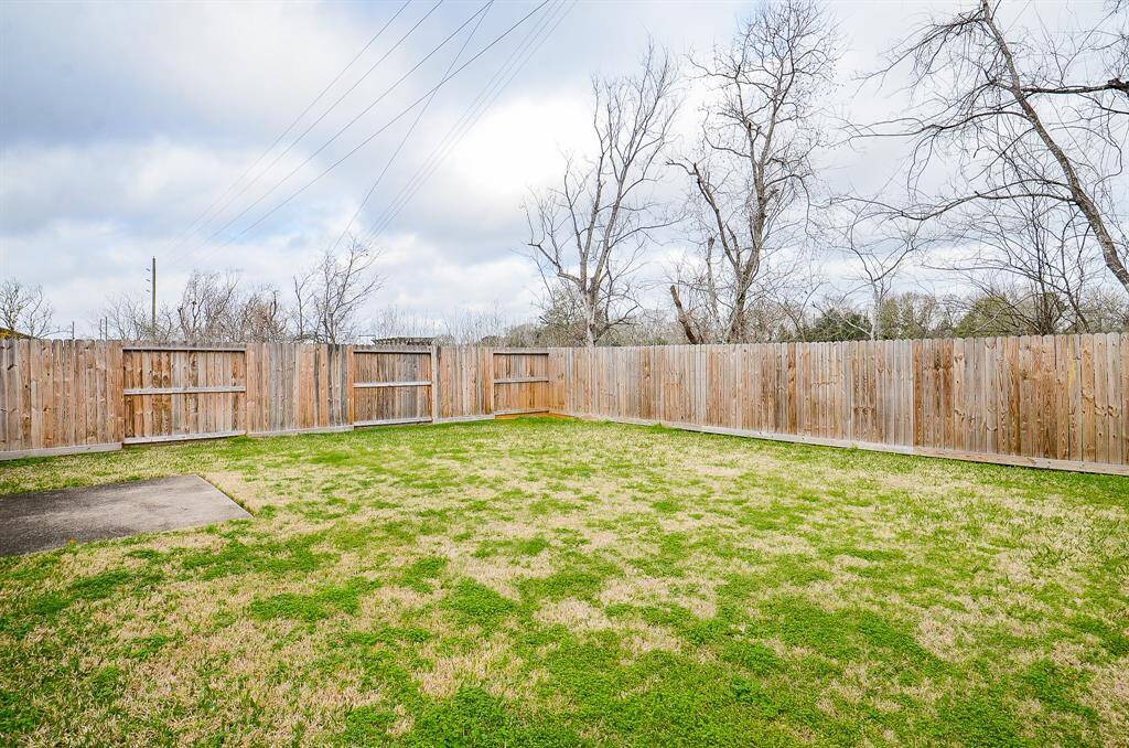 Spacious backyard with a wooden privacy fence and a small concrete patio, ideal for outdoor activities and entertaining.