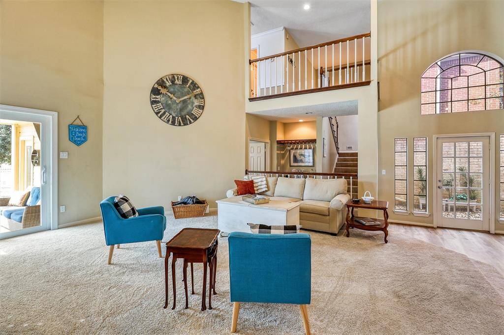 Beautiful view of soaring 2-story family room and staircase to second floor balcony, wet bar, and doorway leading into outdoor atrium.
