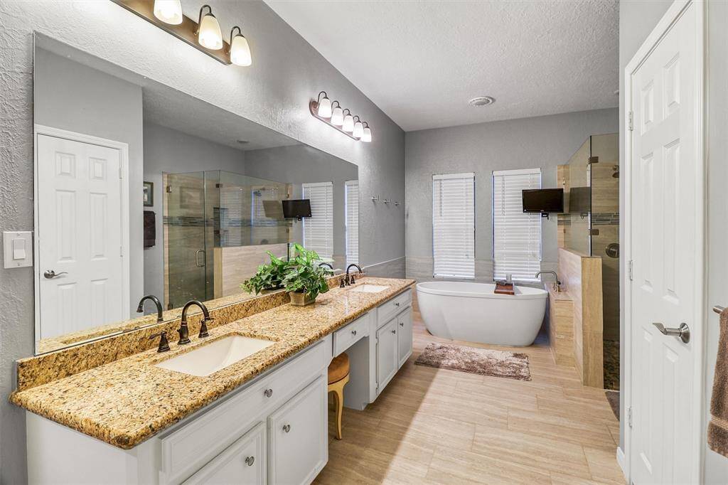 Large remodeled primary en-suite features long granite counters with his and her sinks, lots of cabinets for storage, and private water closet.