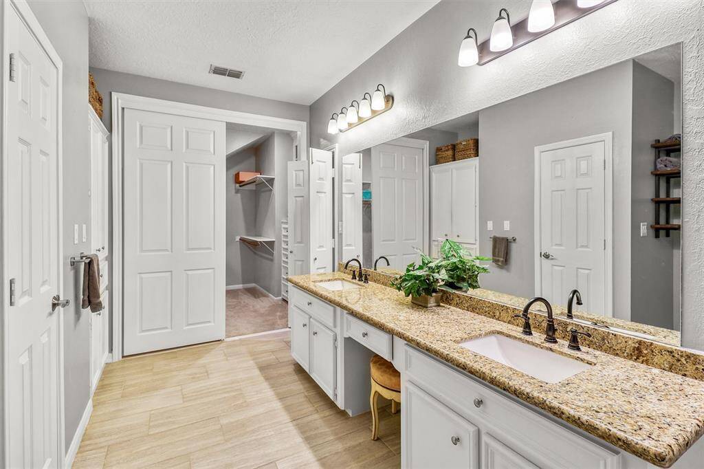 Another view of large remodeled primary en-suite looking towards large walk-in closet which features built-ins and cedar closet/storage area.