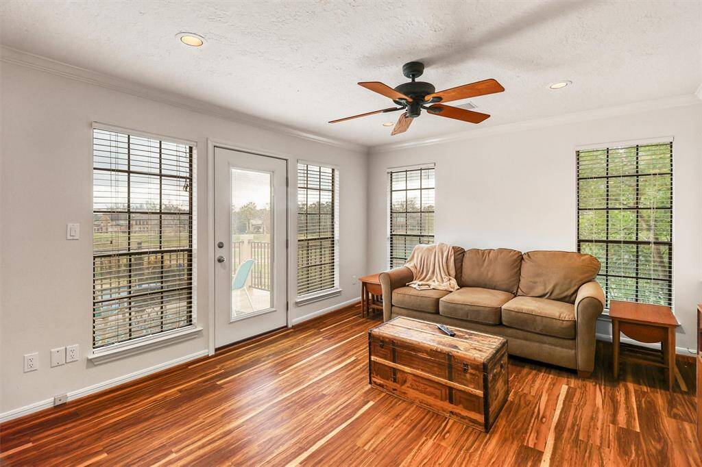 Second floor living area features large windows again for lots of natural light, ceiling fan, and doorway leading to second floor tiled balcony.