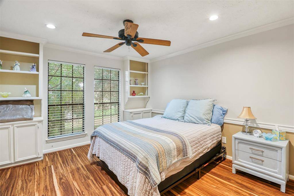 Large upstairs secondary bedroom features crown molding, ceiling fan, large windows for lots of natural light, as well as built-in shelving and cabinets.