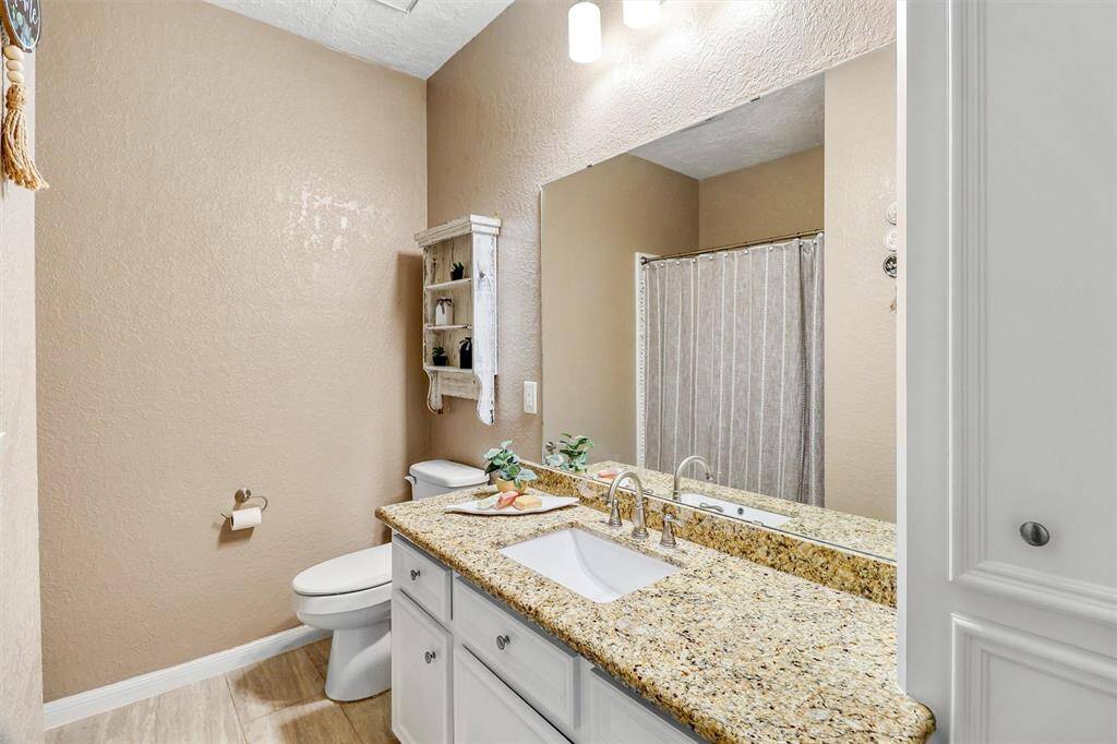 Downstairs full secondary bathroom features long granite counter, built-in cabinets for lots of storage, and tub/shower combination.