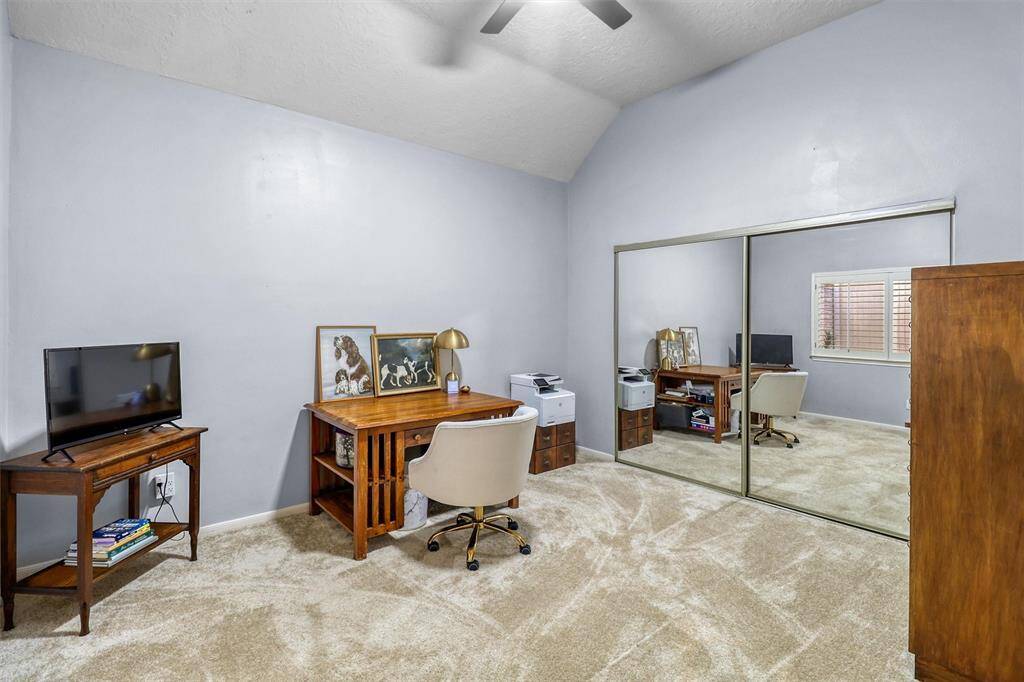 Large first floor secondary bedroom features ceiling fan, coffered ceiling, and double mirrored closet doors, and fresh carpet.