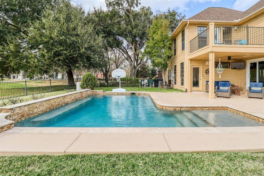 Imagine relaxing or playing games in this beautiful pool featuring travertine coping, cool deck decking, stairs into pool, and long in-pool bench seat.