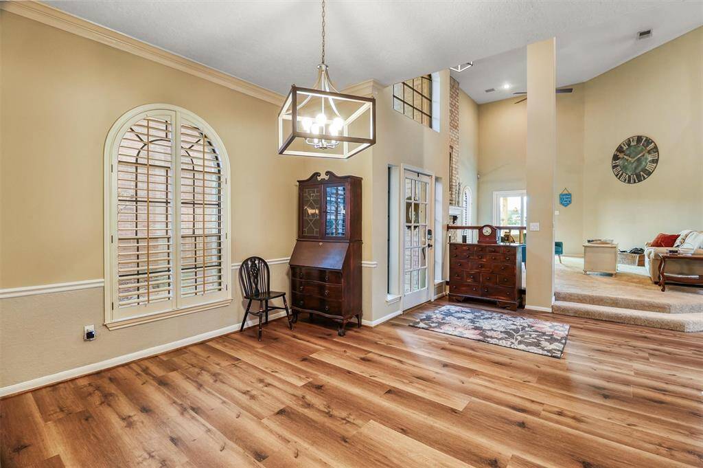 View of dining and open foyer leading into 2-story family room from kitchen entrance featuring large windows with shutters offering lots of natural light.