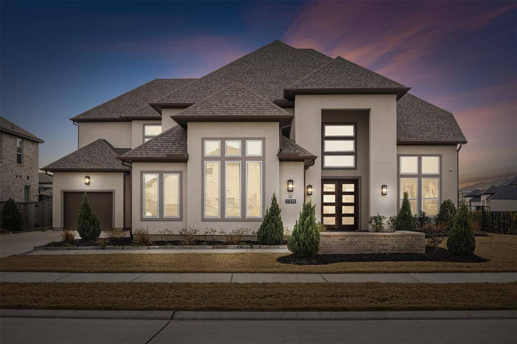 Modern, two-story home with a well-maintained front yard and contemporary architecture. Large windows and elegant exterior lighting complement the stylish facade, creating an inviting atmosphere.