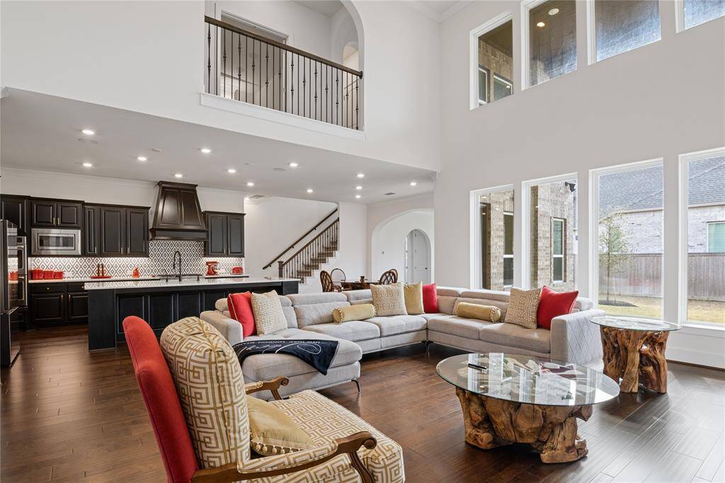 This spacious living area features high ceilings, abundant natural light, and an open floor plan. A staircase leads to a second level, enhancing the home's airy and expansive feel.