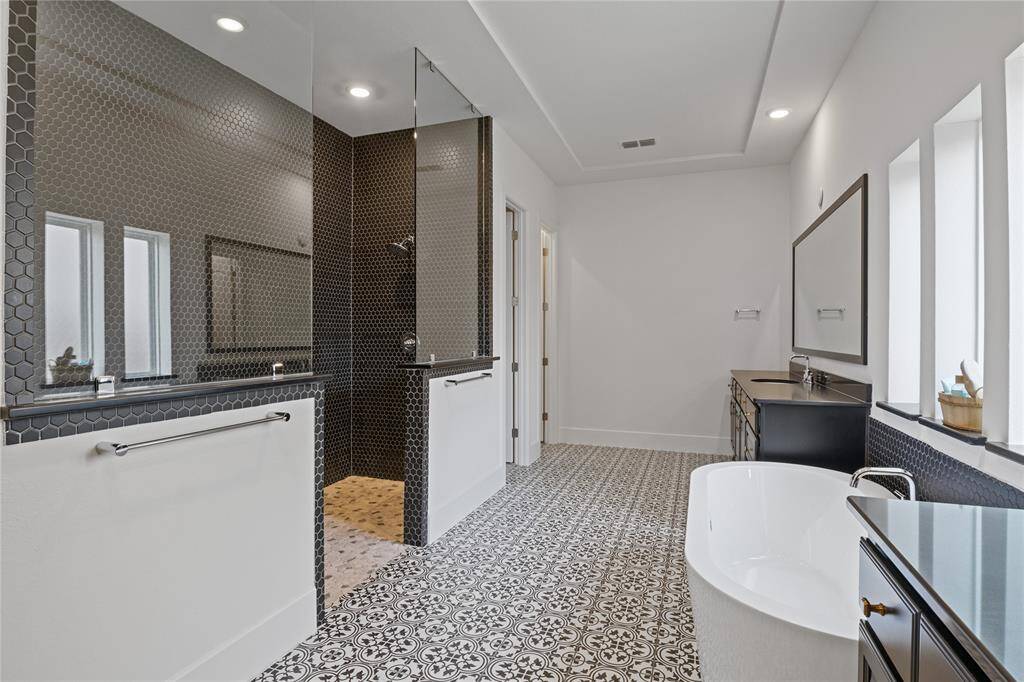 Luxurious primary bathroom featuring a stunning walk-in shower, elegant free-standing tub, and stylish tile flooring. Perfect for relaxation and rejuvenation.