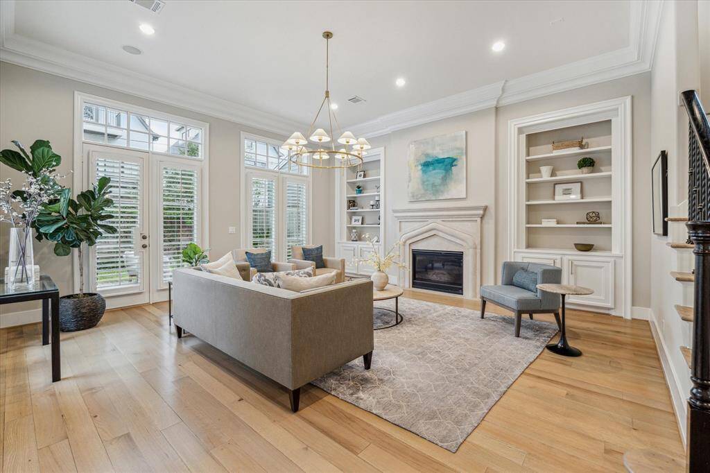 FAMILY ROOM.   A wonderful, light filled and sunny room thanks to floor to ceiling windows.  Build ins sit either side of a stunning cast stone gas log fireplace.   Chandelier - Circa lighting by J. Randall Powers.