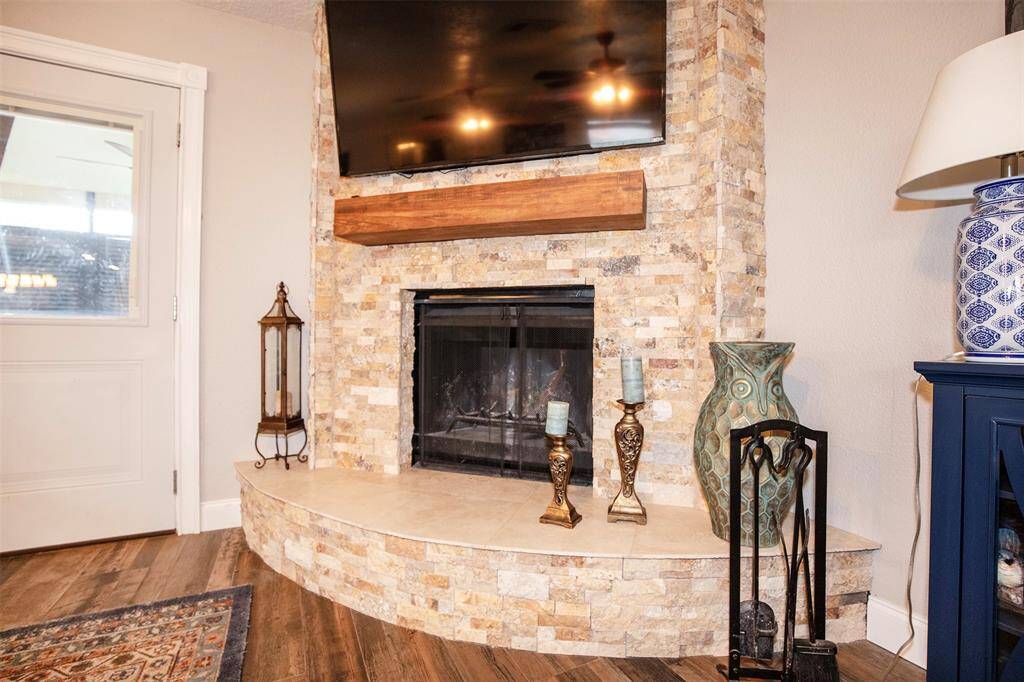 Cozy living area with a stylish stone fireplace, wooden mantel, hardwood flooring and neutral tones create a warm ambiance.