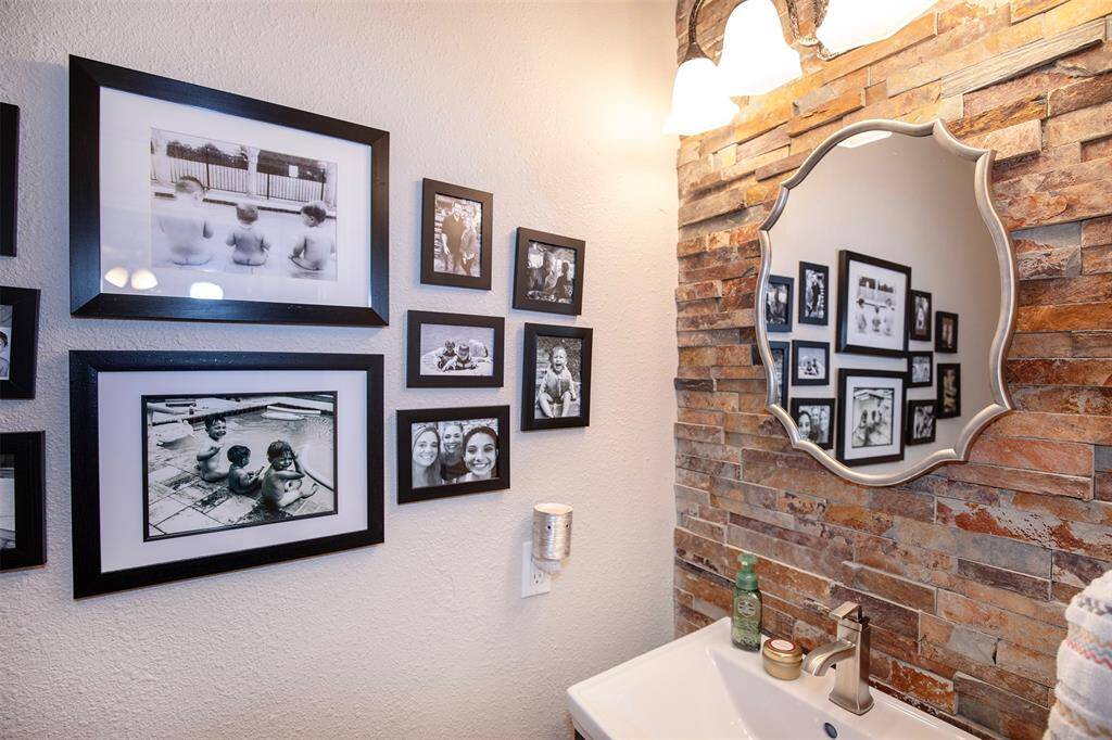 This photo showcases a stylish kitchen area with a sleek black granite countertop and overhead pendant lighting. It features modern cabinetry with wine storage, a decorative mosaic backsplash, and leads into a cozy dining space with a chandelier. The wood flooring adds warmth to the open layout.