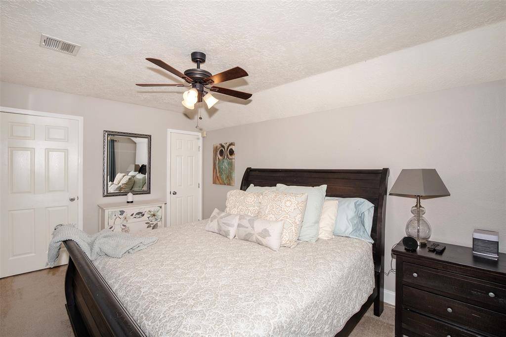 This cozy bedroom features a stylish ceiling fan, and soft carpeting.