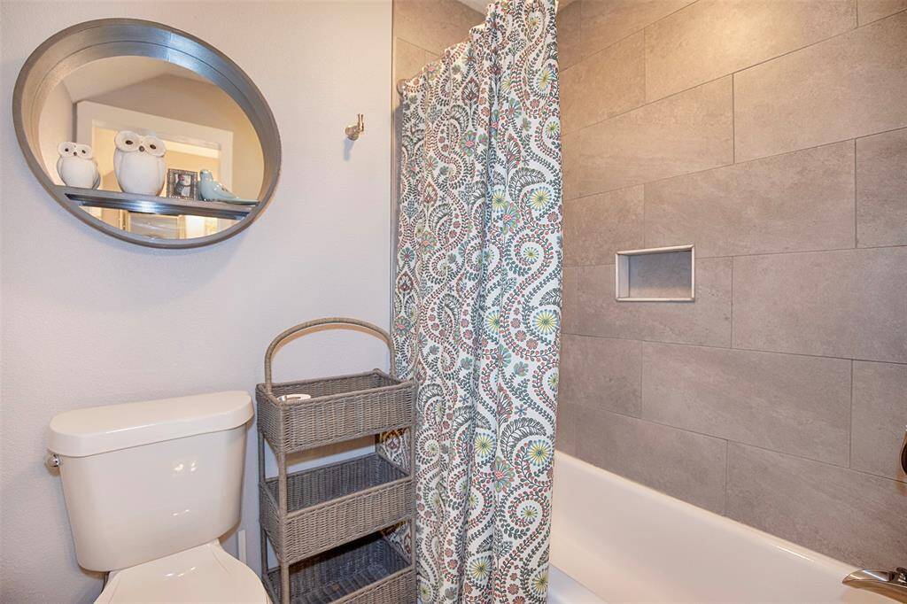 This updated en-suite bathroom features a large tiled shower, modern double vanity with granite countertops and under-mount sinks. It includes elegant black-framed mirrors, natural lighting and stylish light fixtures.