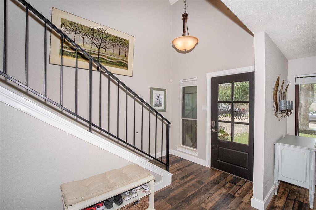 This photo showcases a warm and inviting dining room with hardwood floors and a stylish chandelier. The space opens up to a cozy living area, enhancing the open-concept feel.