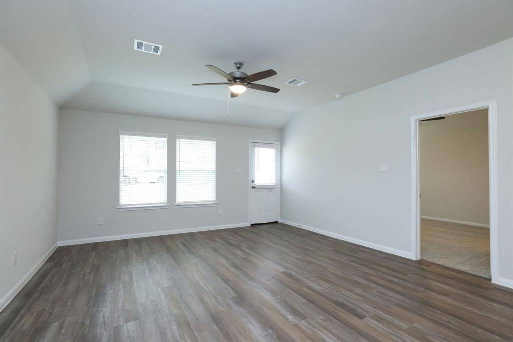 The bright and spacious living room with neutral walls, and a lighted ceiling fan is ready for binge watching your favorite tv shows.