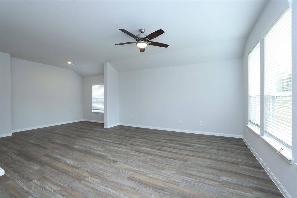 The bright and spacious living room with neutral walls, and a lighted ceiling fan is ready for binge watching your favorite tv shows.