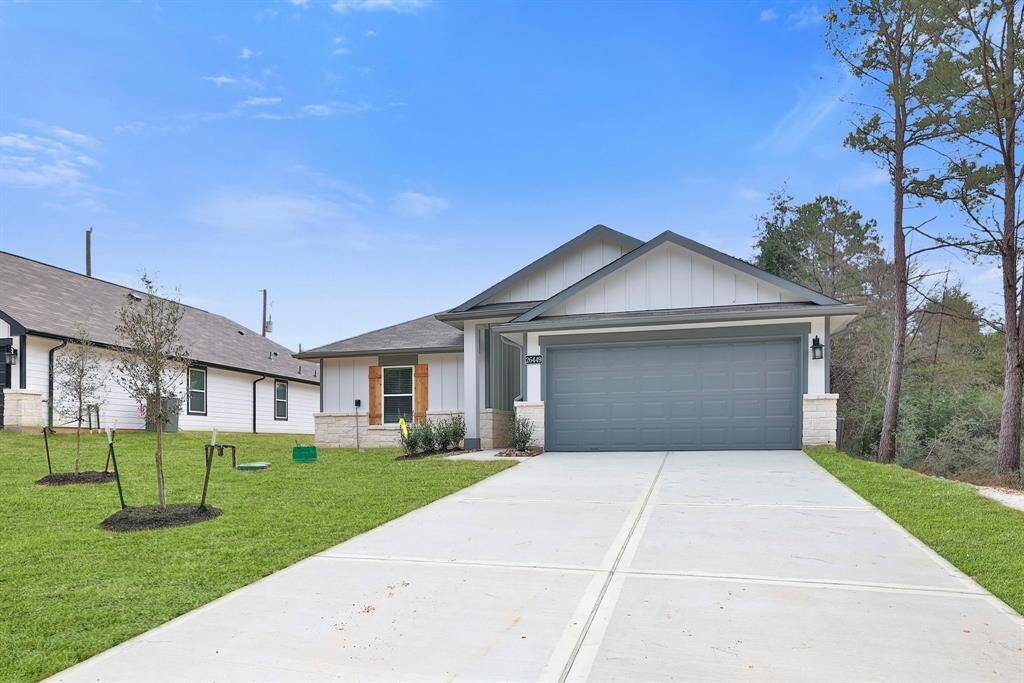 The rustic feel of a Texas home comes to light with the stone and wood features on the exterior. It includes a two-car garage, a welcoming front porch with a wooden door, and a neatly landscaped yard with newly planted trees.