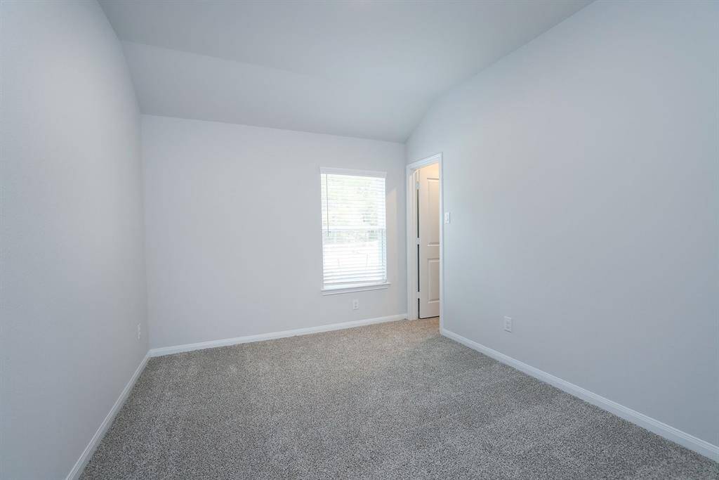 Bedroom #2 offers a single window dressed with blinds, and neutral carpet flooring. It features a simple white door and overhead lighting, ideal for a bedroom or office space.